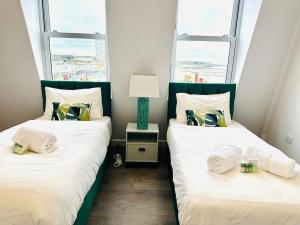 two beds in a room with two windows at Seaview apartment in Kent in Kent