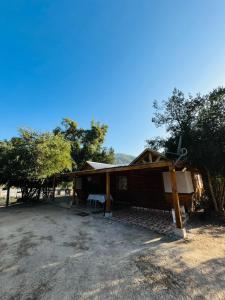 ein Haus auf einem Feld mit Bäumen im Hintergrund in der Unterkunft Cabaña en linares camino el embalse ancoa in Linares