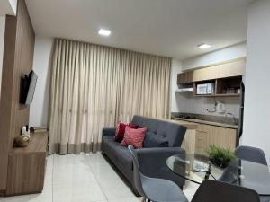 a living room with a blue couch and a glass table at Apto c/vista próx a faculdade /hospitais PC2302 in Goiânia