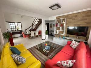 a living room with a red couch and a tv at Casa para Família com Lazer Total - Próximo Aeroporto in Lauro de Freitas