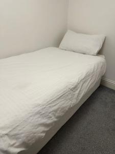 a bed with white sheets and a pillow on it at Single Room In A Cosy House In Pitsea in Pitsea