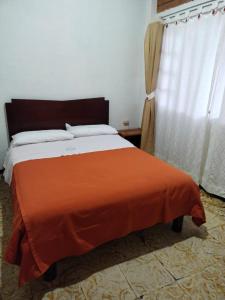 a bedroom with a bed with an orange blanket at Hotel y Cabañas Rio Mayo in Chachagüí