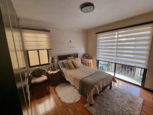 a bedroom with a bed and a large window at Comodidad y Elegancia in Cochabamba