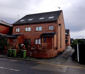 a red brick house with a black roof at Jacks Court B2 in Stalybridge