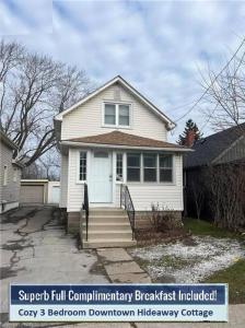 a white house with a white door and stairs at Cozy 3 Bedroom Downtown Hideaway Cottage with Complimentary Breakfast in Niagara Falls