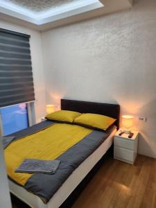 een slaapkamer met een bed met gele kussens en een raam bij Apartman Relja in Novi Banovci