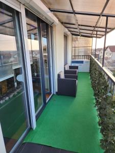 a balcony with green flooring in a building at Apartman Relja in Novi Banovci