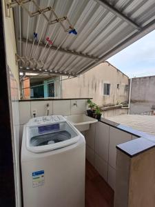 Un lave-linge est installé sous un auvent sur un balcon. dans l'établissement Lindo AP inteiro de um quarto próximo a praia., à Vila Velha