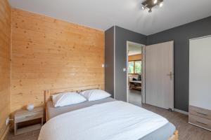 - une chambre avec un lit blanc et un mur en bois dans l'établissement Chalets du Bouchot & Jacuzzi privatif proximité Gerardmer & La Bresse, à Rochesson