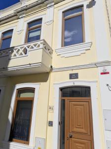 a yellow building with a wooden door and windows at Figueira da Foz Luxury Villa Suite Room in Buarcos