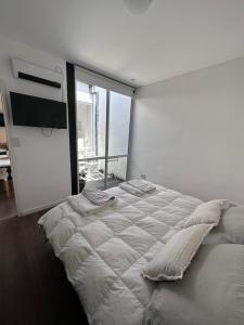 a white bedroom with a large bed and a large window at PATAGONIA FLAT in Esquel