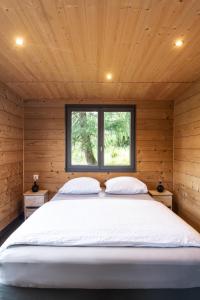 a bed in a wooden room with a window at Chalet du Faubourg & Jacuzzi, proximité Gerardmer & La Bresse in Rochesson