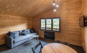 a living room with a couch and a tv and a table at Chalet du Faubourg & Jacuzzi, proximité Gerardmer & La Bresse in Rochesson