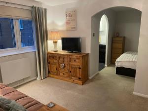 a living room with a television on a wooden dresser at Beautiful Peaceful Studio Flat in Waltham Abbey