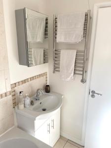 a white bathroom with a sink and a mirror at Beautiful Peaceful Studio Flat in Waltham Abbey