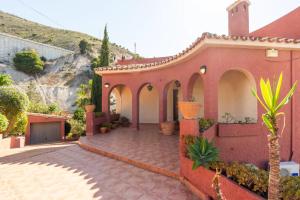 una casa roja con un patio con plantas en Villa Romeo, with brand new salt water pool, en Benalmádena