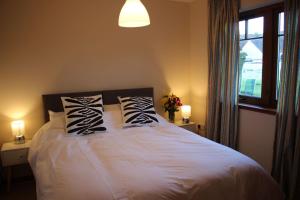 a bedroom with a white bed with pillows and a window at Taigh Munro in Aviemore