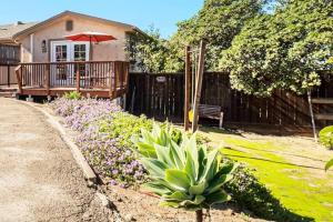 a house with a garden with flowers and an umbrella at One bedroom retreat full kitchen/laundry 1GB Wi-Fi in Bonita