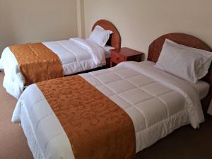 a hotel room with two beds and a night stand at Hotel Casa Shami in Cusco