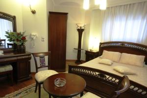 a bedroom with a bed and a desk and a table at Aegeon Hotel in Karlovasi