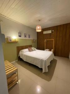 um quarto com uma cama branca num quarto em Casa Araucarias Refugio Natural en la Ciudad em Posadas