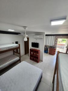uma sala de estar com uma cama e uma televisão em Hospedaria Ilhabela - Flats Sul em Ilhabela