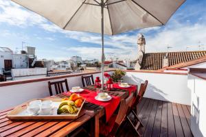 a table with a tray of food on a balcony with an umbrella at Bo&Co Apartments in Sitges