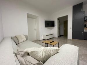 ein weißes Wohnzimmer mit einem Sofa und einem Tisch in der Unterkunft Kleine moderne 3-Bett Wohnung/Apartment 