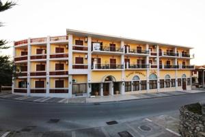 a large white building with balconies on a street at Aegeon Hotel in Karlovasi