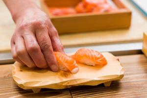 eine Person, die Orangen auf einem Schneidebrett zerschneidet in der Unterkunft Kyukamura Fuji in Fujinomiya