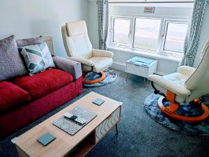 a living room with a red couch and two chairs at Seahawk Holiday Apartments in Cleveleys