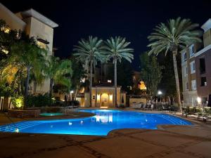 a swimming pool at night with palm trees and a building at Luxury Modern Condo 3-min from Six Flags w/PS5, 1GB Fast Wi-fi Kingbed in Santa Clarita