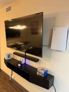 einen an der Wand eines Zimmers hängenden Fernseher in der Unterkunft Luxury Modern Condo 3-min from Six Flags w/PS5, 1GB Fast Wi-fi Kingbed in Santa Clarita