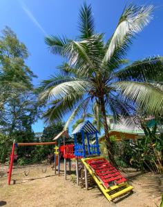 un parque infantil junto a una palmera con un columpio en Ocean Blue Condos in Jacó, en Puntarenas