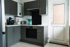 a kitchen with dark gray cabinets and a window at Cosy 2BR Flat - Beach Nearby in Kent