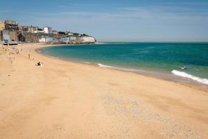 a sandy beach with people swimming in the ocean at Cosy 2BR Flat - Beach Nearby in Kent