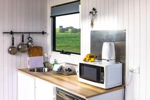 a kitchen counter with a microwave and a sink at Bedervale Tiny in Braidwood