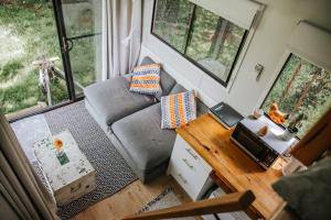 sala de estar con sofá y escritorio con ordenador portátil en Bedervale Tiny, en Braidwood