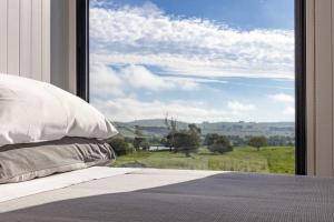 a bedroom with a window with a view of a field at Bedervale Tiny in Braidwood