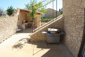 a grill outside of a brick wall with a patio at Les Pres de Gordes in Gordes