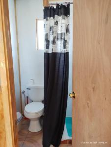 a bathroom with a toilet and a black shower curtain at Cabaña Precordillera Cunco in Cunco