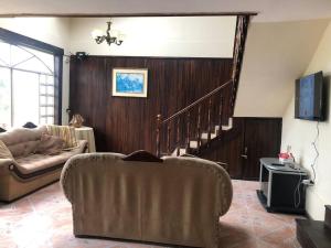 sala de estar con sofá y escalera en Casa de campo Country house in Yunguilla, Cuenca, Ecuador, en Cuenca