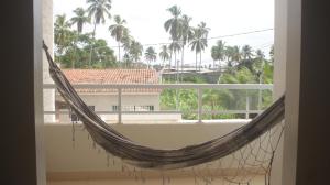 een hangmat op een balkon met palmbomen bij Casamoura in Maragogi