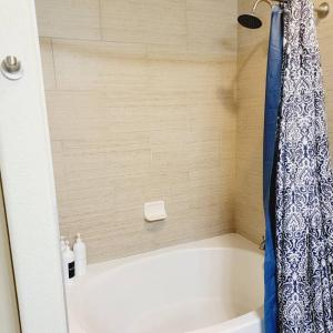 a bath tub with a blue and white shower curtain at Relaxing Pool View Apt Reliant Stadium/Medical Center in Houston