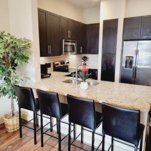 a kitchen with a large island with black bar chairs at Relaxing Pool View Apt Reliant Stadium/Medical Center in Houston