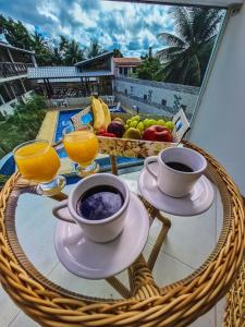 - une table avec deux tasses de café et une corbeille de fruits dans l'établissement Village Encantado, à Guarajuba