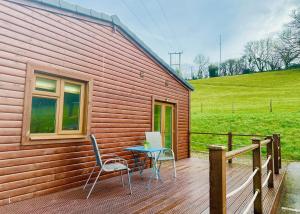 a wooden deck with a table and chairs on it at Pant Wilkin Lodges And Equestrian Centre in Cowbridge