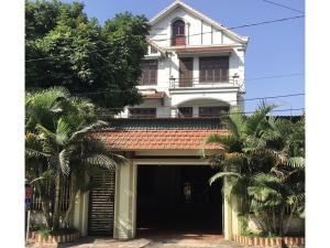 une maison blanche avec des palmiers devant elle dans l'établissement Minh Tâm Hotel ( Nhà Nghỉ Minh Tâm ), à Vĩnh Phúc
