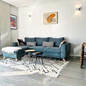 een woonkamer met een blauwe bank en een tafel bij Studio Taghazout Bay avec grand jardin in Taghazout