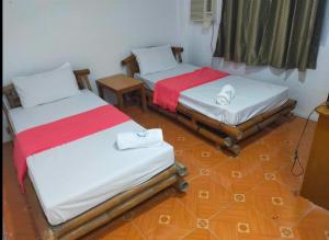 two twin beds in a room with wooden floors at Auzone Inn Budget Hometel in Locsin